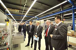 Jens Torkel, Managing Director (im Bild rechts), erläutert Gästen die Verpackung von Zahnpasta auf der High-Speed Tubenfüllmaschine "TFS 80-6".