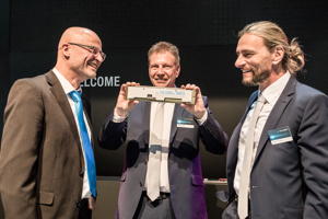 Tobias Schlier, Business Manager bei Schubert System Elektronik, überreicht eine goldene WK3 an Ralf und Gerald Schubert, der zum Übergabezeitpunkt noch im Unternehmen tätig war.