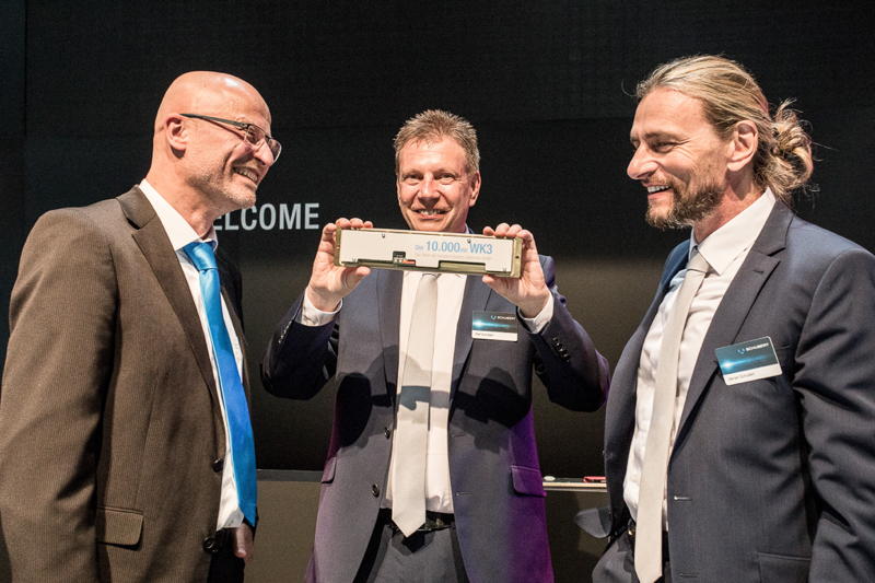 Tobias Schlier, Business Manager bei Schubert System Elektronik, überreicht eine goldene WK3 an Ralf und Gerald Schubert, der zum Übergabezeitpunkt noch im Unternehmen tätig war.