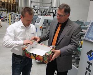 BayPack-Betriebsleiter Manfred Mayr (links) und Baumer hhs-Vertriebsleiter Markus Leier richten eine Obst- und Gemüsesteige auf, wie sie BayPack typischerweise für seine Kunden herstellt.