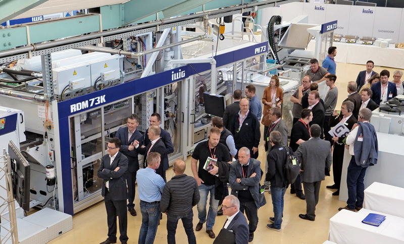 Visitors of the Illig Open house venue in front of the thermoforming machine RDM73K.