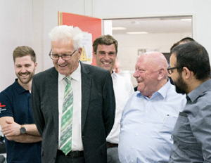 Ministerpräsident Winfried Kretschmann und Firmengründer Gerhard Schubert im Gespräch mit dem Entwicklungsteam des Cobot-Labors.