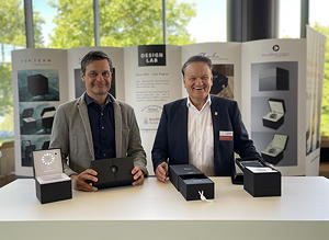 Thilo Mühle (links), Geschäftsführer Mühle-Glashütte und Udo Hollbach, Geschäftsführer Koehler Paper Standort Greiz halten die Mockups der ökologischen Luxusverpackung aus 100 % Recyclingpapier auf der PRINT & DIGITAL CONVENTION in den Händen.