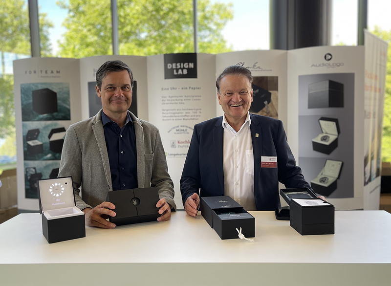 Thilo Mühle (links), Geschäftsführer Mühle-Glashütte und Udo Hollbach, Geschäftsführer Koehler Paper Standort Greiz halten die Mockups der ökologischen Luxusverpackung aus 100 % Recyclingpapier auf der PRINT & DIGITAL CONVENTION in den Händen.