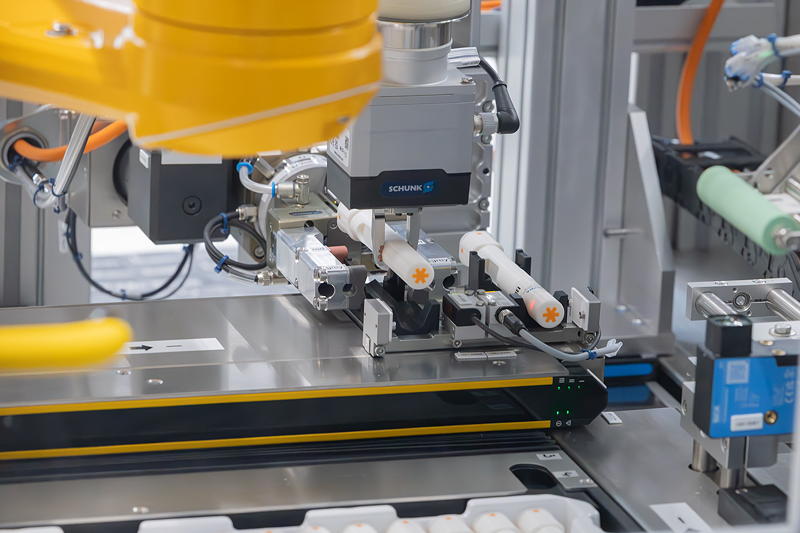 Stable automated handling even with complex product geometries: As the gripper
places a labeled autoinjector back into the tray, the transport and rotation
unit already moves a new product toward the labeler’s dispensing edge.